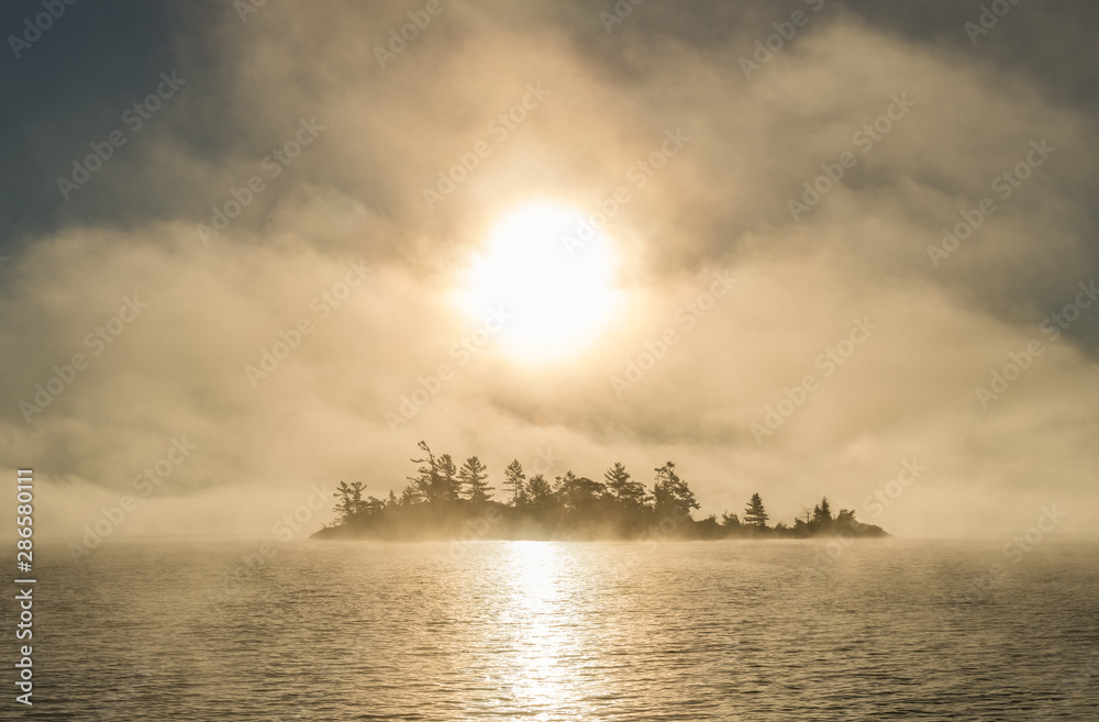 Foggy-morning sun rising over island in the 30,000-island archipelago of the Georgian Bay, Ontario, Canada. Foggy-morning sun rising over island in the 30,000-island archipelago of the Georgian Bay, Ontario, Canada.