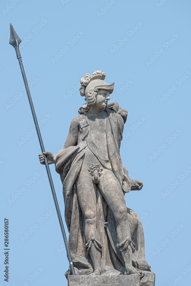 Ancient top roof statue of a naked knight in armor and with a spire in Potsdam at blue sky, Germany