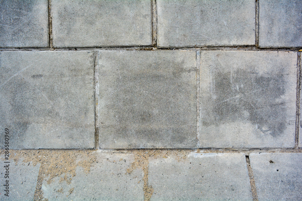 Fototapeta premium Large square cement street floor slabs. Texture of gray dirty tiles pavement
