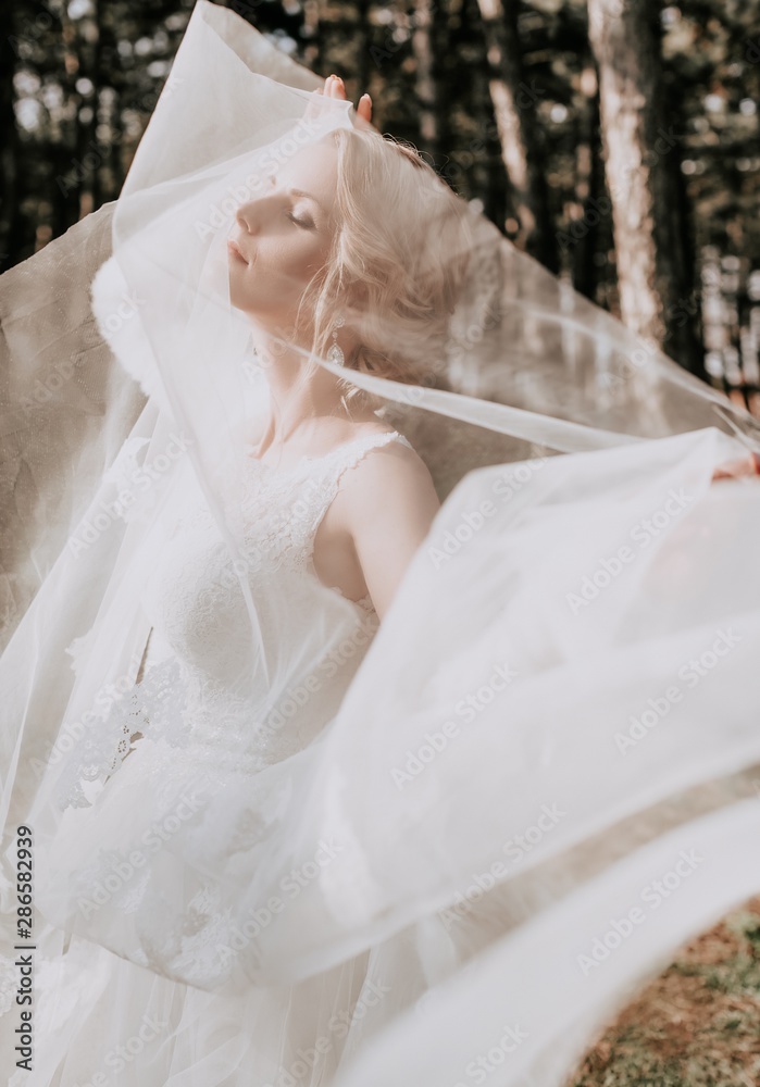 Beautiful blonde bride with stylish make-up in white dress in the garden Beautiful blonde bride with stylish make-up in white dress in the garden