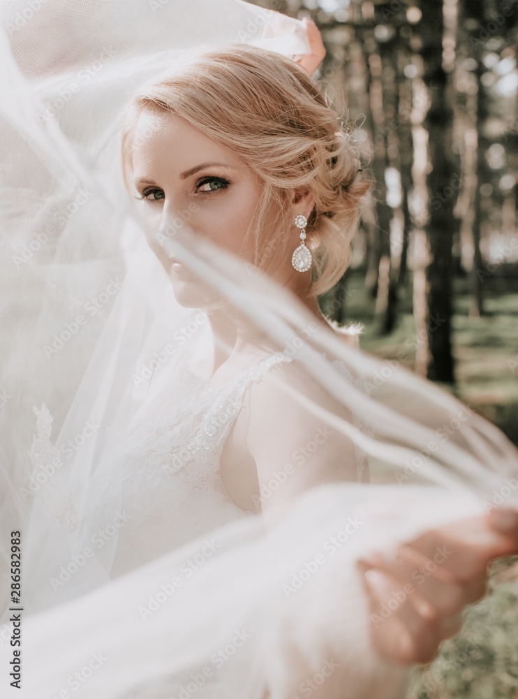 Beautiful blonde bride with stylish make-up in white dress in the garden Beautiful blonde bride with stylish make-up in white dress in the garden