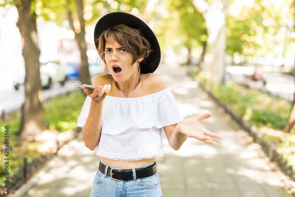 Shocked angry woman scream on smart phone discovering mistake content in the street Shocked angry woman scream on smart phone discovering mistake content in the street