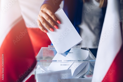 Woman putting her vote to ballot box. Poland political elections photo