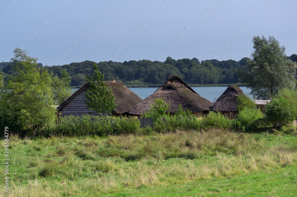 Historic thatched roof houses in the viking village of Hedeby on the banks of the river Schlei in Northern Germany, copy space