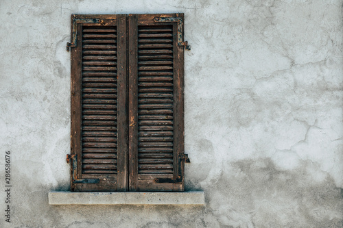 old window with wooden shutters with cracked wall