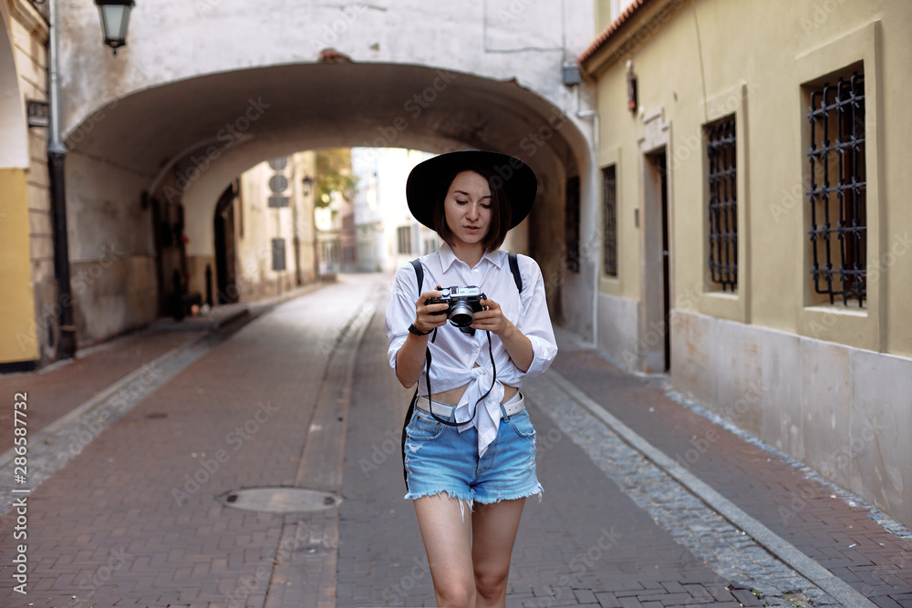 The girl in the black hat shooting in an old european town.