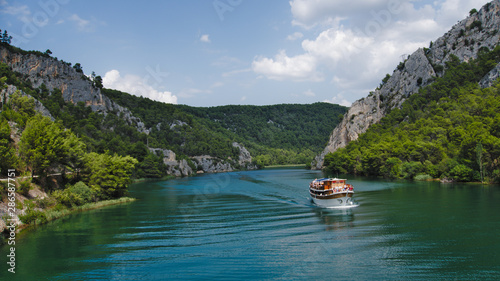 A boat flowing down the river with mountains in the background