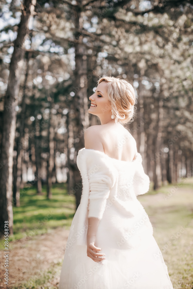 Beautiful blonde bride with stylish make-up in white dress in spring garden Beautiful blonde bride with stylish make-up in white dress in spring garden
