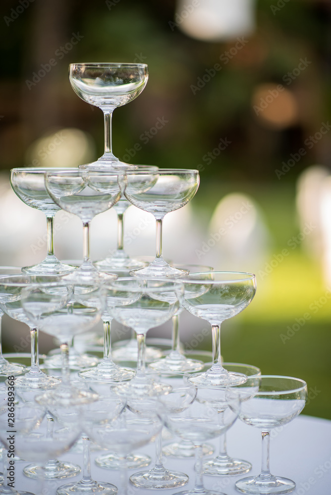 Pyramid of glasses of champagne at outdoor garden in wedding ceremony