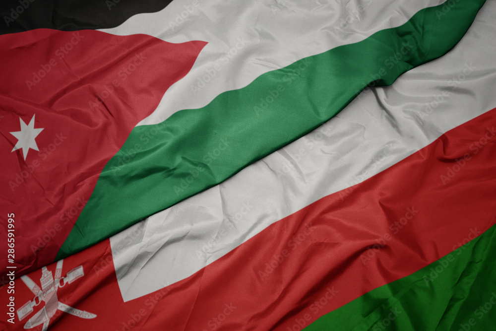 waving colorful flag of oman and national flag of jordan.