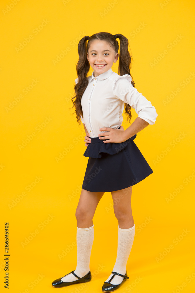 Exciting back to school style. Happy small girl holding long ponytail hair style on yellow background. Little child smiling in formal style. Giving school fashion a sense of style Exciting back to school style. Happy small girl holding long ponytail hair style on yellow background. Little child smiling in formal style. Giving school fashion a sense of style