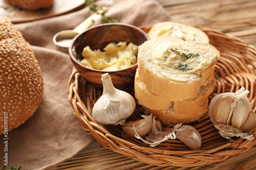 Slices of fresh bread with butter, herbs and garlic on table