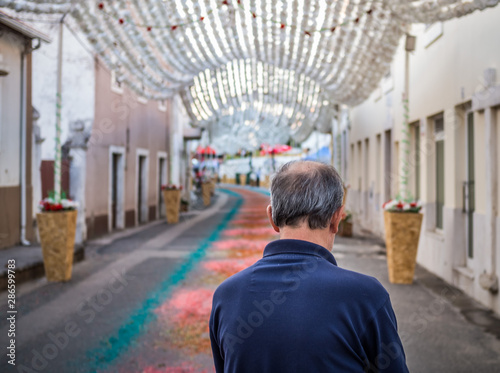 Old man with hat seen from behind walking down the street