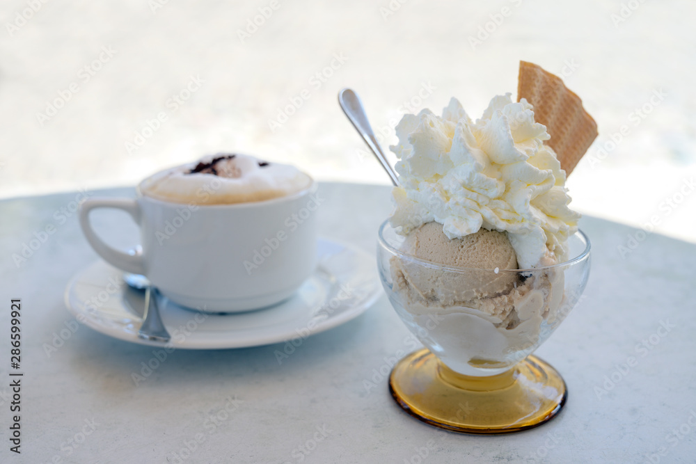 Ice cream sundae and a cup of cappuccino on a table in a street cafe, copy space