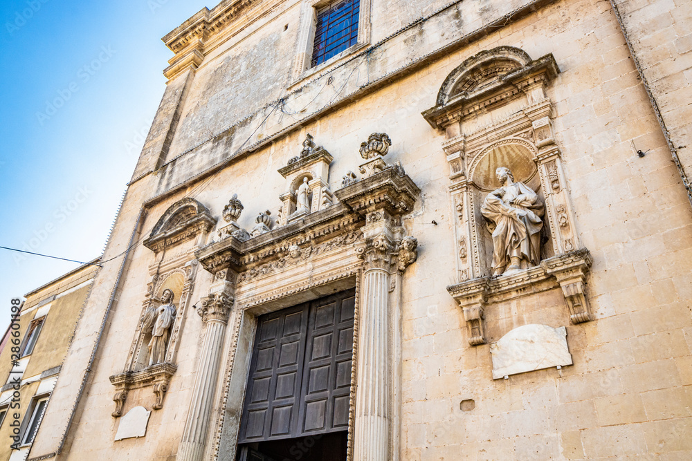 The mother church of Cavallino, Lecce, Puglia, Salento, Italy. In baroque style. Wooden portal and niches with statues on the sides, on the facade.