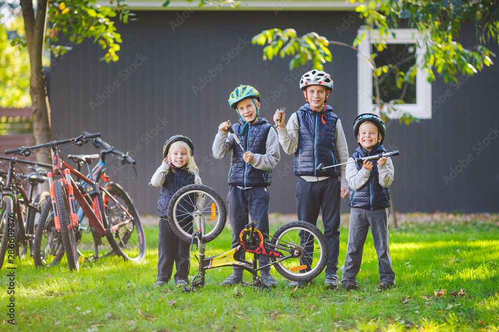 Children mechanics, bicycle repair. Happy kids fixing bike together