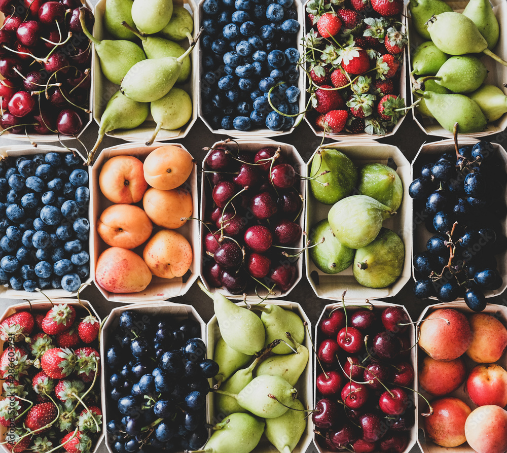 Naklejka Letni asortyment owoców i jagód. Płaskie ułożenie truskawek, wiśni, winogron, jagód, gruszek, moreli, fig w ekologicznych pudełkach na szarym tle, widok z góry, zbliżenie. Lokalni rolnicy produkują