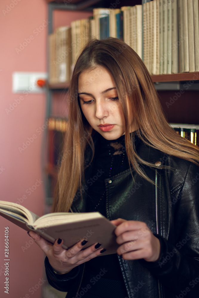 Beautiful teenager schoolgirl reading a book in the library Beautiful teenager schoolgirl reading a book in the library