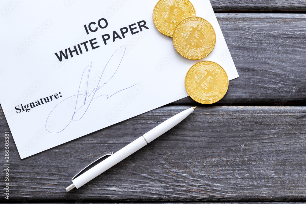 Initial coin offering ICO white paper, bitcoin, pen on gray wooden background top view