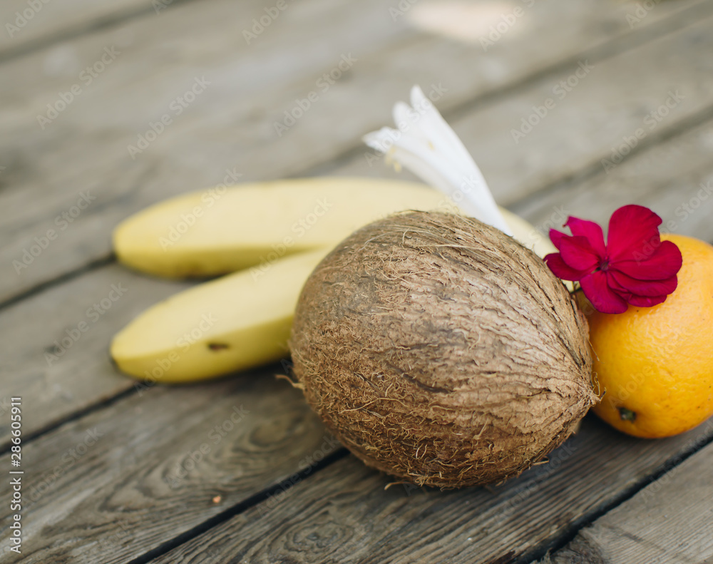 Tropical fruit on the wooden background. Cope space. Fruits background. Coconut, oranges and bananas on a wooden table. Tropical fruit on the wooden background. Cope space. Fruits background. Coconut, oranges and bananas on a wooden table.