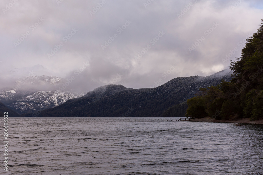 Scene view of Futalaufquen lake against snow-capped Andes mountains on a gray day in Los Alerces National Park, Patagonia, Argentina