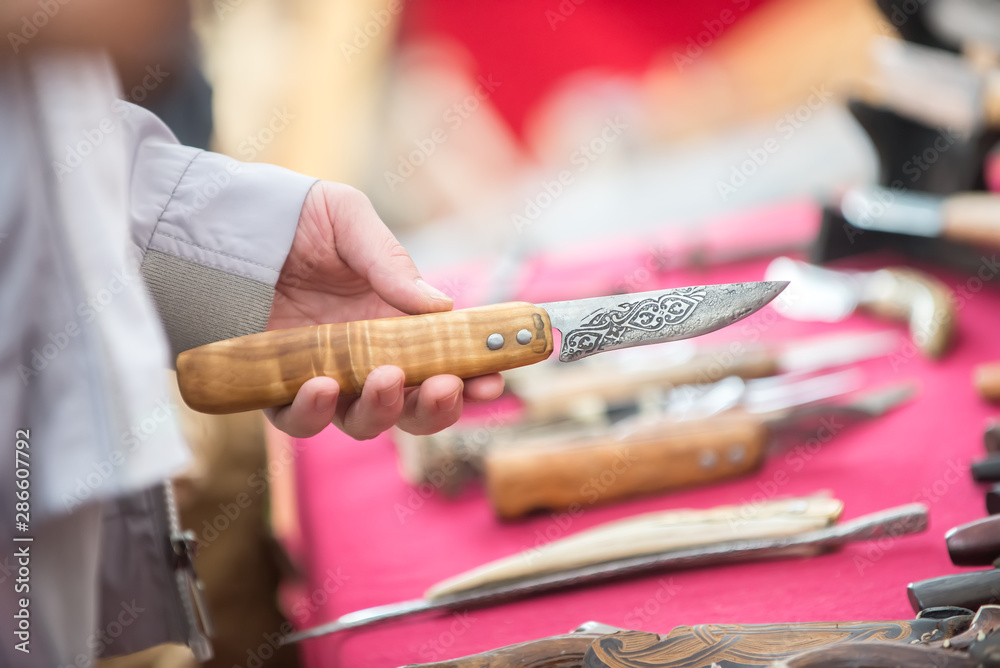 Handmade knife in a man's hand at the fair. The concept of craft and needlework.