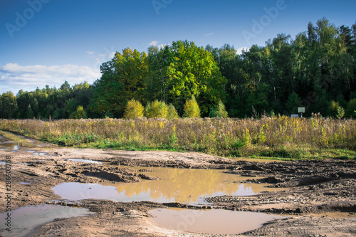 dirty country road among the endless forests and fields after heavy rains somewhere in Eastern Europe.The beginning of autumn 2018
