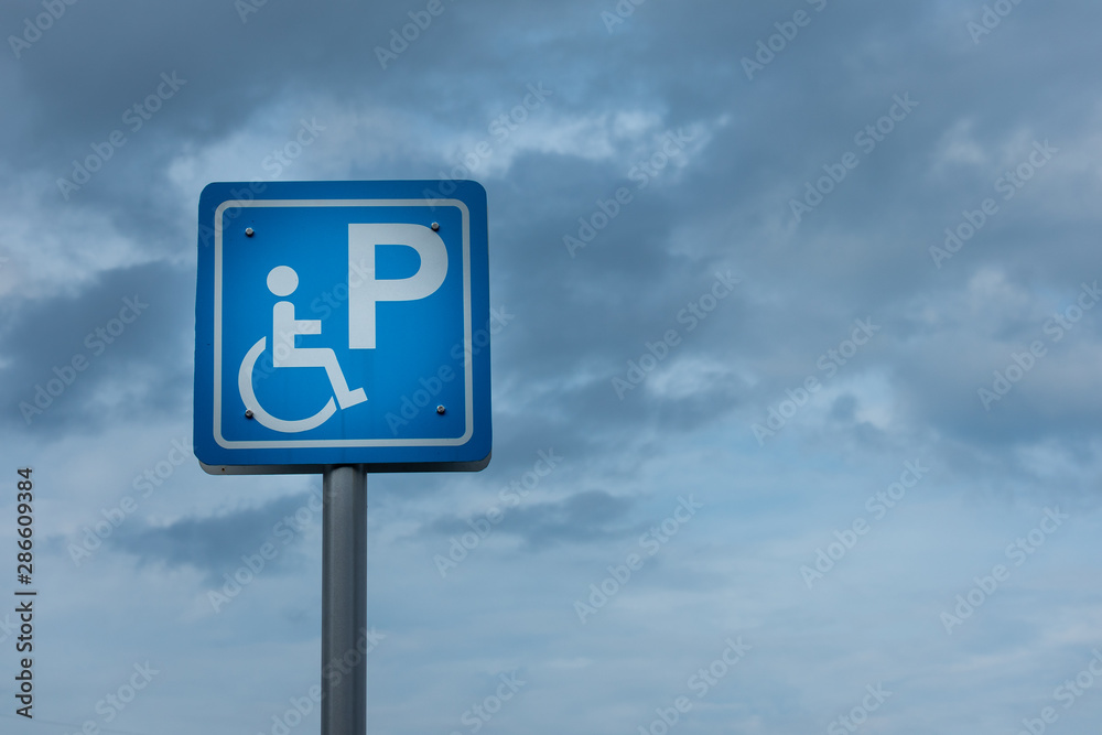 Disabled parking sign on the sky,Slope way sign for wheelchair people on blue sky background - Handicapped parking,disable parking road sign with a wheelchair sky background.with copy space Disabled parking sign on the sky,Slope way sign for wheelchair people on blue sky background - Handicapped parking,disable parking road sign with a wheelchair sky background.with copy space