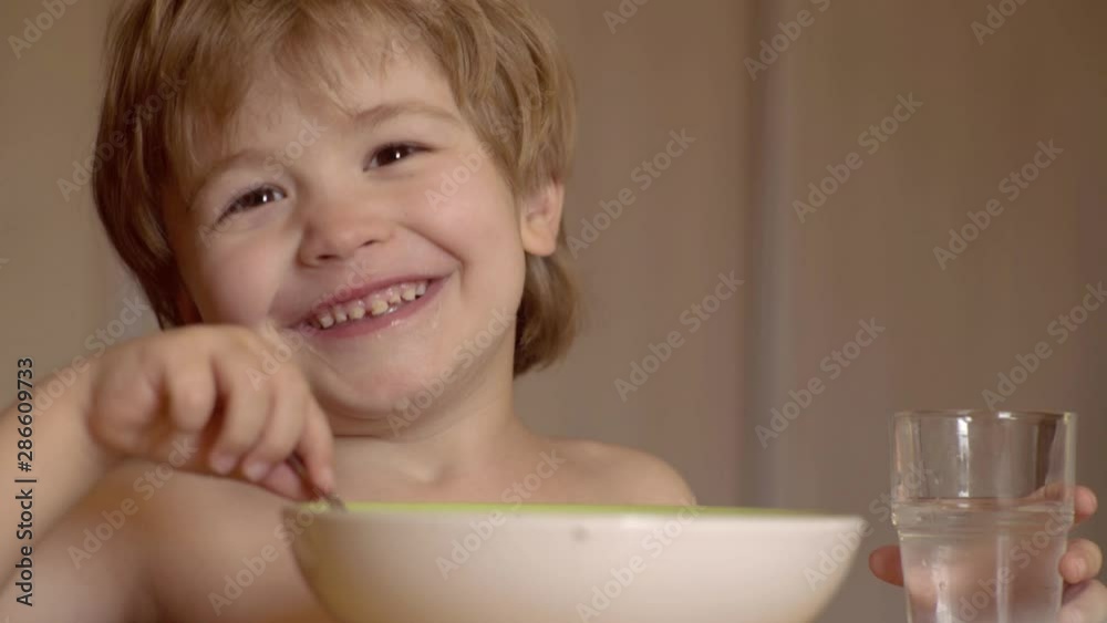 Parenthood. Portrait of beautiful child having breakfast at home. Cute child eating breakfast at home. Smiling happy adorable baby eating fruit mash in the kitchen. Parenthood. Portrait of beautiful child having breakfast at home. Cute child eating breakfast at home. Smiling happy adorable baby eating fruit mash in the kitchen.