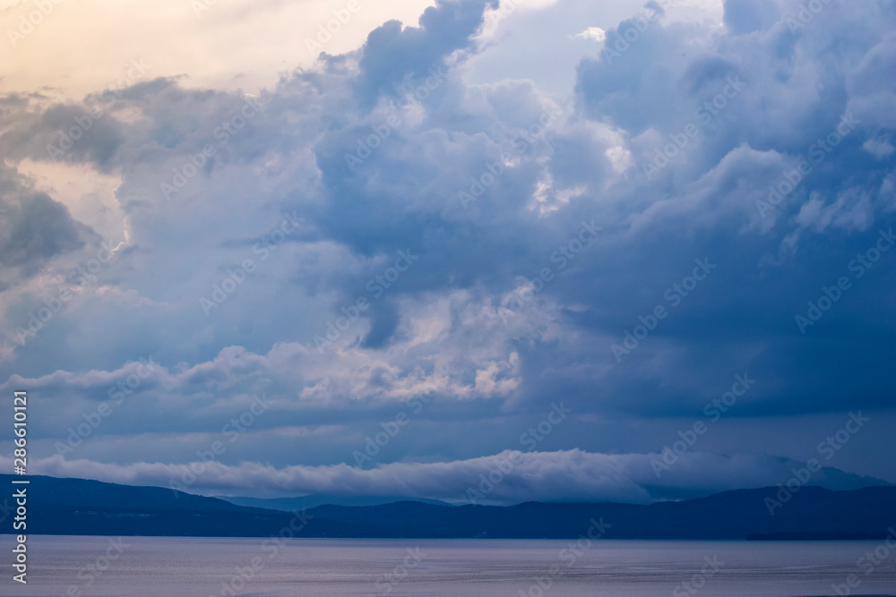 Fototapeta premium Dramatic clouds over lake and mountains at dusk