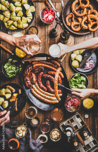 Slika na platnu Flat-lay of Octoberfest party dinner table with grilled sausages, pretzel pastry