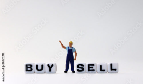 The white cube of 'BUY' and 'SELL' text with miniature people.