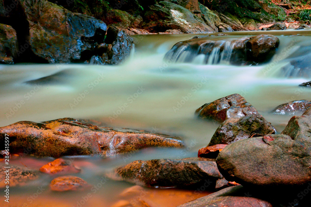 Obraz premium Beautiful River water flowing through stones and rocks at dawn