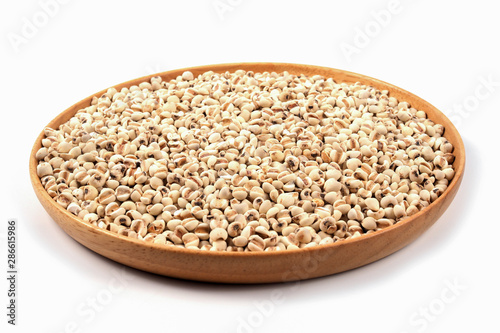 Organic millet grains on brown wood dish on white background.