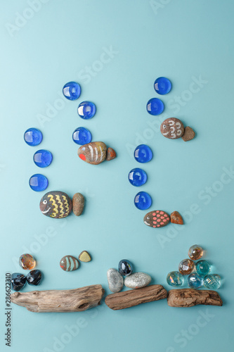 Diy painted stone fish on blue background and sea decoration. Creative DIY idea, surreal imagination kids world. Kid handmade, kindergarten, daycare concept.