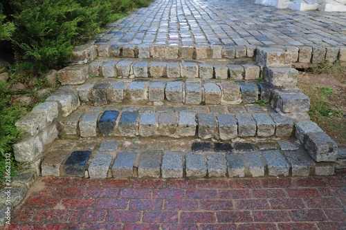 Selective focus of old stone, brick stair and walkway pavement in the park with green trees. Park and outdoor concept.