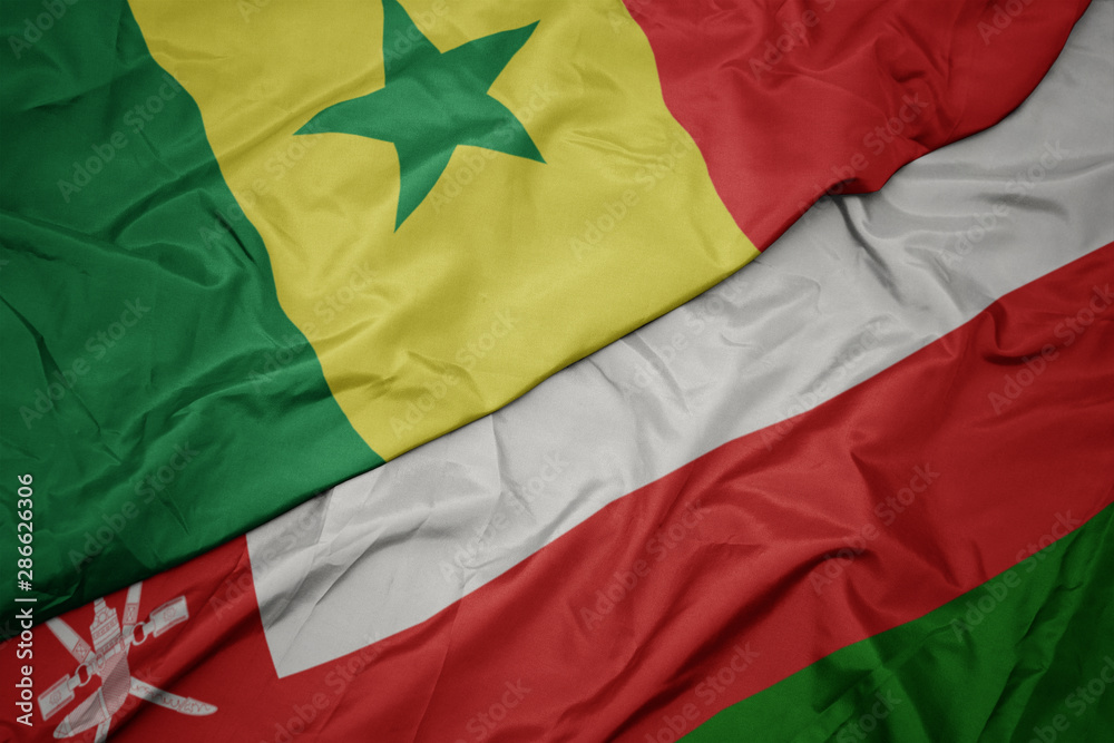 waving colorful flag of oman and national flag of senegal.