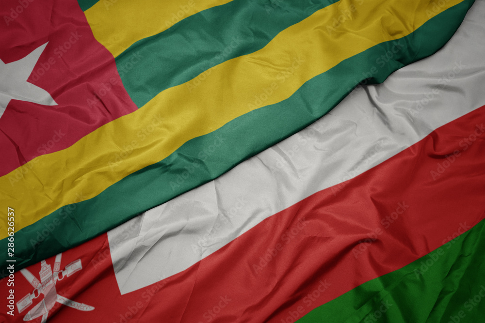 waving colorful flag of oman and national flag of togo.
