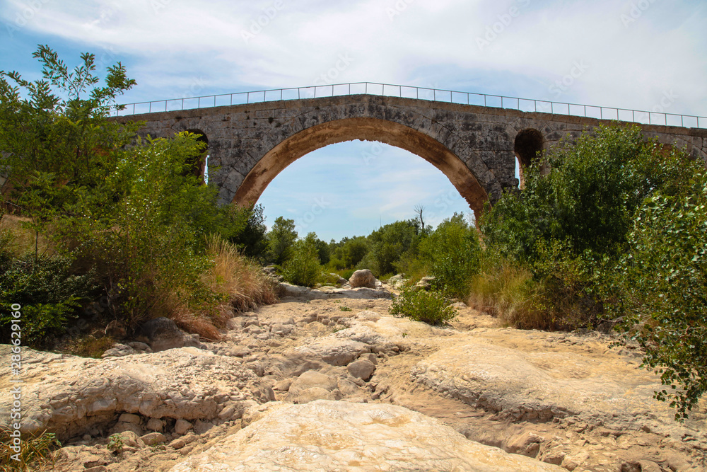 Charming stone bridge across mountain river. France.