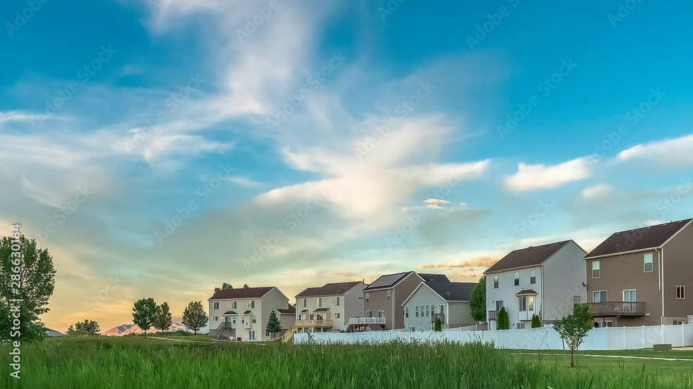 Panorama Expansive terrain covered with rich green grasses in front of family homes