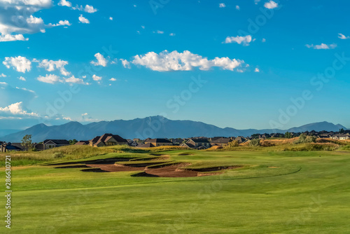 Picturesque view of a golf course with residences and mountain in the background