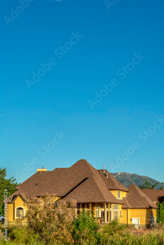 Home with brown roof and yellow wall against mountain and clear blue sky