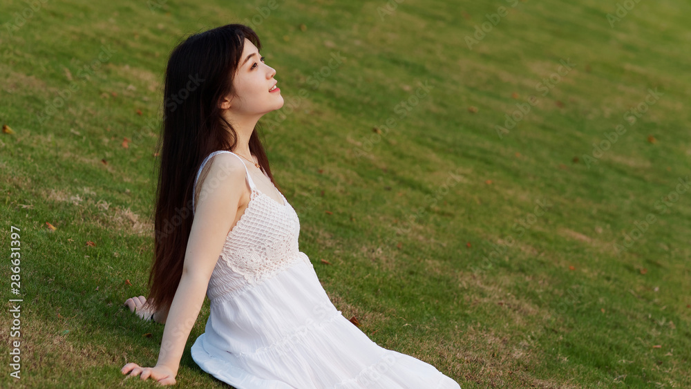 Portrait of beautiful Chinese young woman in white wedding dress sitting on grass field with hand on ground, beauty in summer. Portrait of beautiful Chinese young woman in white wedding dress sitting on grass field with hand on ground, beauty in summer.