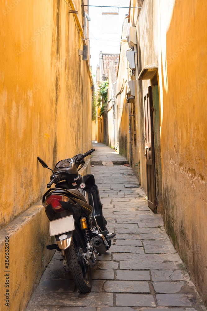 Parked motorcycle and yellow walls in alleyway, Hoi An, Vietnam　ベトナム・ホイアンの路地裏