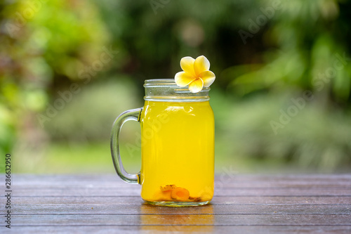 Energy tonic drink with turmeric, ginger, lemon and honey in glass mug, nature background, close up