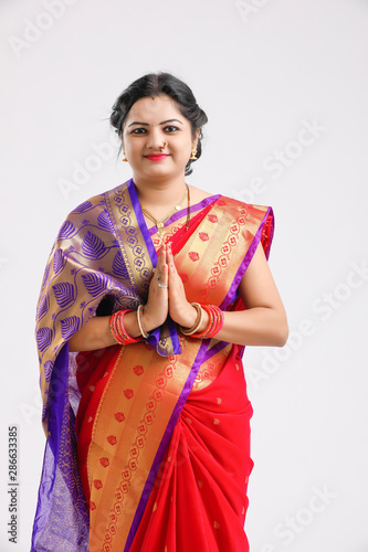  young Indian woman wearing Sari and showing a welcome gestures, isolated on white background