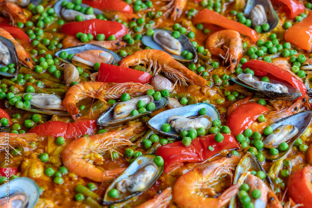 Spanish seafood paella in fry pan with mussels, shrimps and vegetables. Seafood paella background, closeup, traditional spanish rice dish