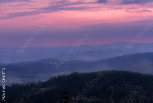 Sunset with distant hill and fog from Tristolicnik. Blue hour. Sumava National Park and Bavarian Forest, Czech republic and Germany