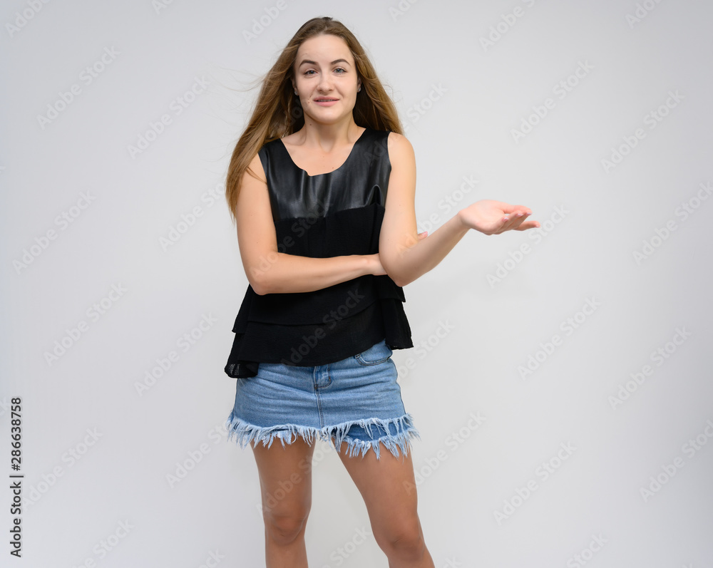 Studio photo portrait of a pretty student girl, young brunette woman with long beautiful hair in denim shorts and a black T-shirt on a white background. Smiling, talking, showing emotions Studio photo portrait of a pretty student girl, young brunette woman with long beautiful hair in denim shorts and a black T-shirt on a white background. Smiling, talking, showing emotions