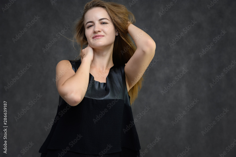 Studio photo portrait of a pretty student girl, brunette young woman with long beautiful hair in a black T-shirt on a gray background. Smiling, talking, showing emotions Studio photo portrait of a pretty student girl, brunette young woman with long beautiful hair in a black T-shirt on a gray background. Smiling, talking, showing emotions